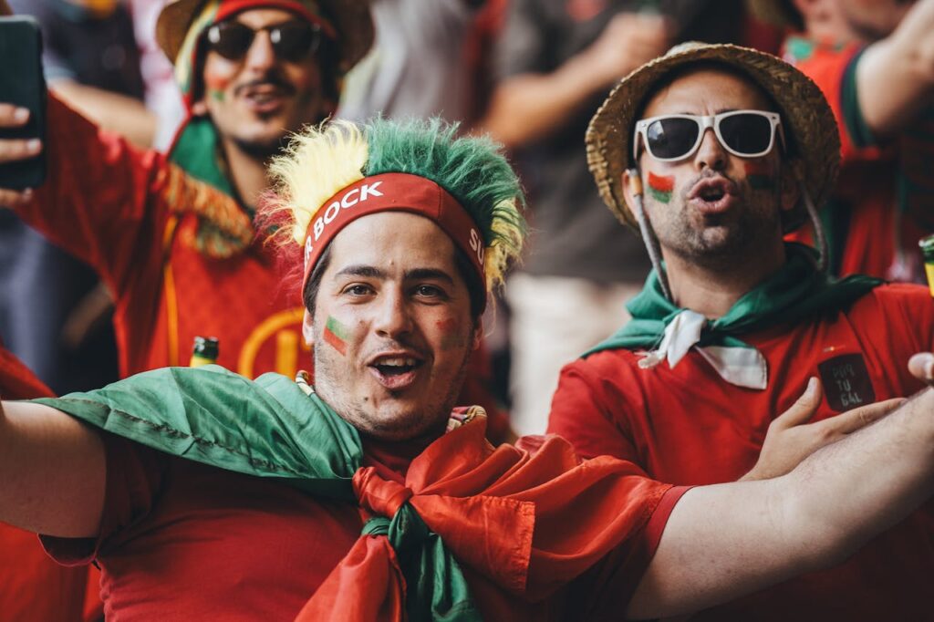 Passionate group of football fans celebrating outdoors with flags and colorful outfits.